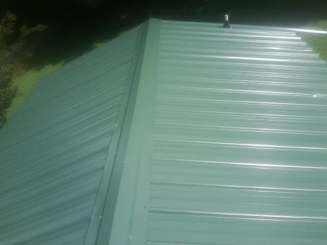 New green metal panels meeting at the ridge of a roof — Flat Roof Repair work by our crew in Sproul