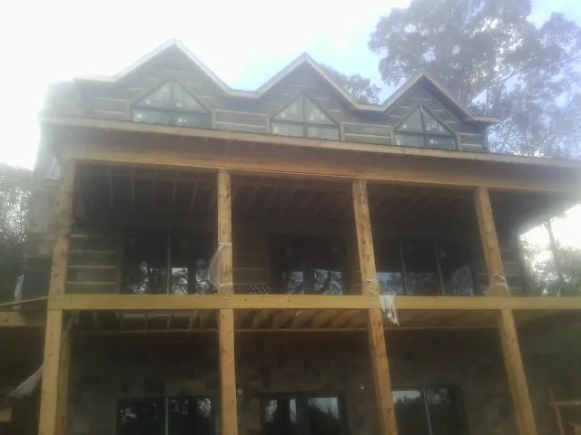 Dormers and porch framing on a large log home under construction — Roof Coating work by our crew in Sproul