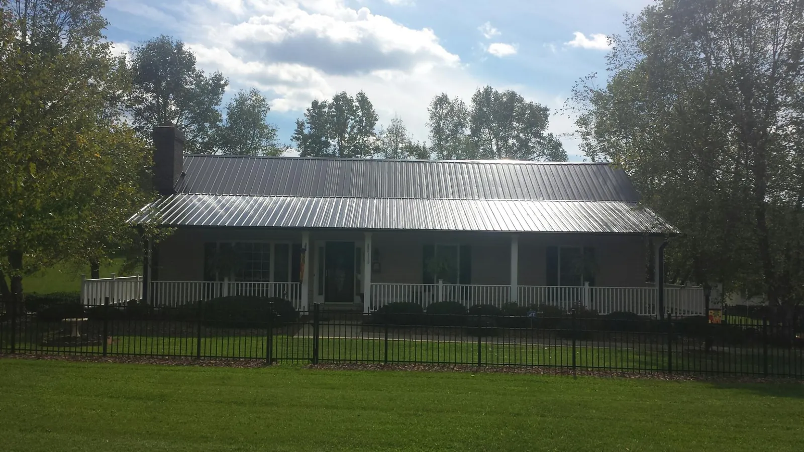 Gray metal roof on a brick ranch with a full width front porch — Gutter Guard Installation work by our crew in Sproul