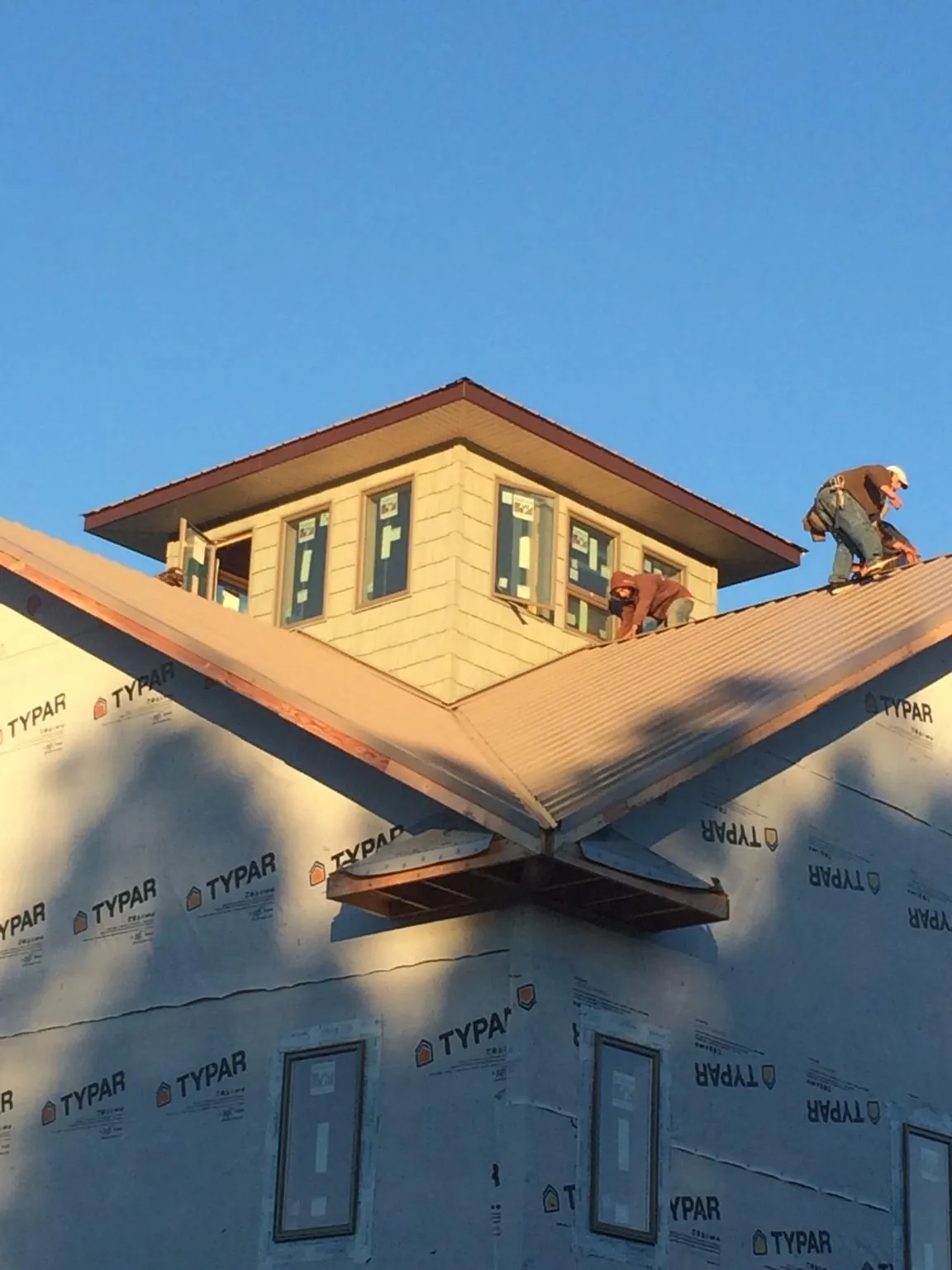 Roofers working around a rooftop cupola on a new metal roof at sunset — Roof Waterproofing in Sproul by Roofing Brothers